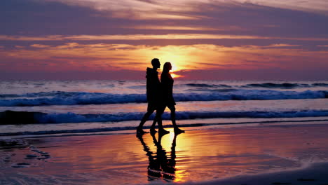 couple walking on beach at sunset