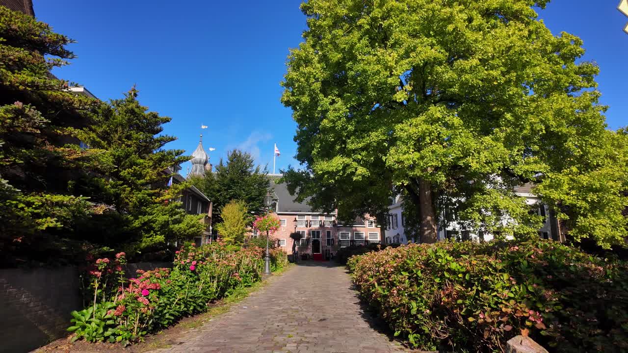 Cobblestone path lined with green trees and shrubs leading towards historic castle entrance in Coevorden, Drenthe. Location: Coevorden, Netherlands – Coevorden, Nederland
