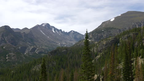 beautiful view over forest valley toward mountain range with snow caps