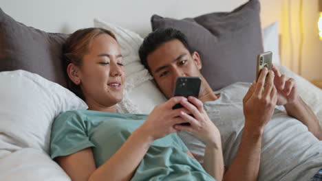 Happy-young-couple-in-bed-on-their-phone-on-social