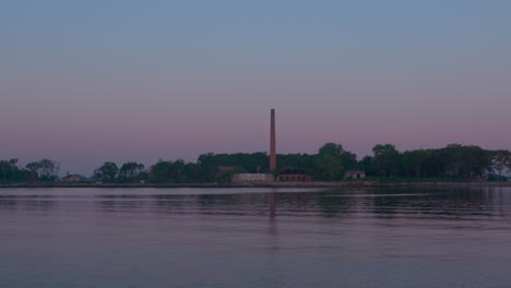 Chimney-at-Hart-Island,-Solemn-burial-site-for-unidentified-dead,-from-the-water-in-the-evening