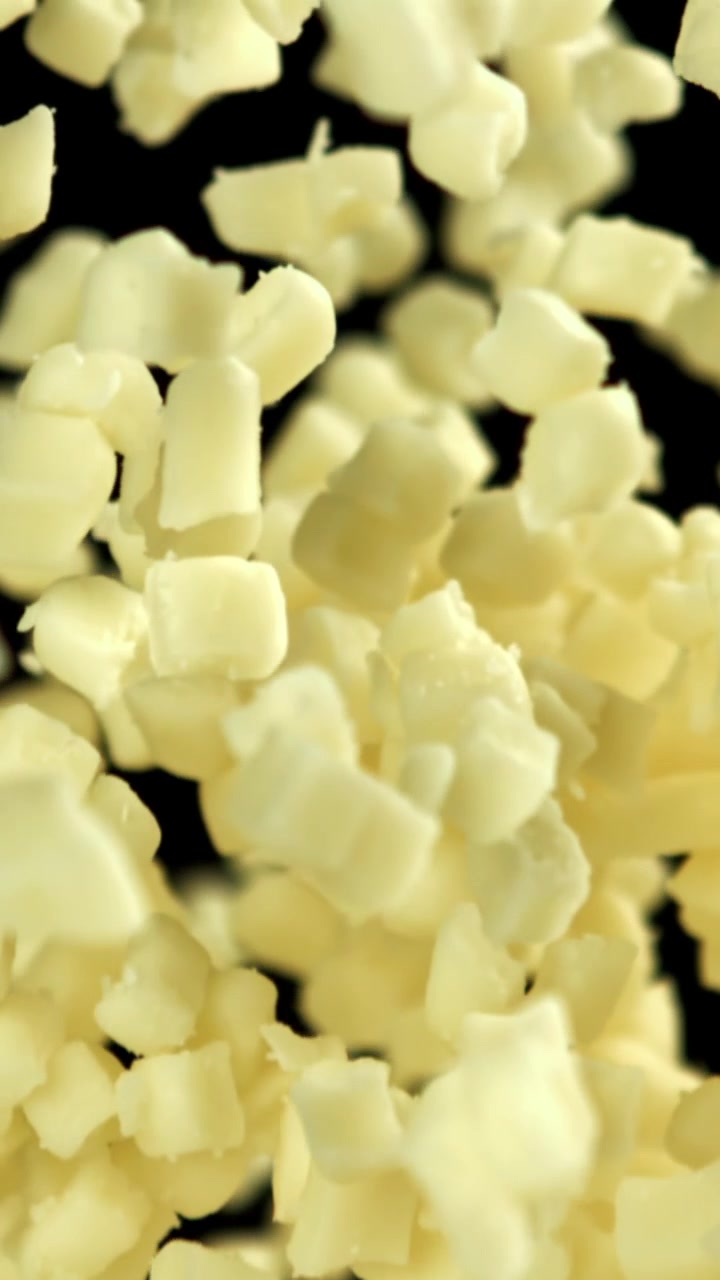 Formaggio a cubetti che cade al rallentatore su sfondo nero