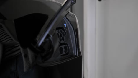 Close-up-on-hand-plugging-in-charger-into-electric-car-at-charge-station