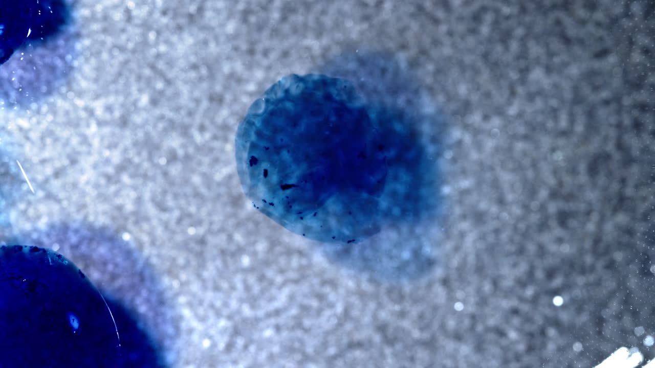 Blue alcohol ink blooming on textured surface, abstract macro art in motion