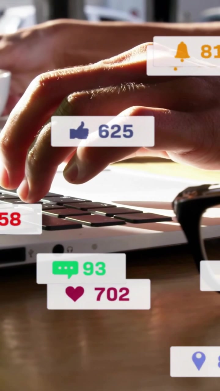 Vertical video: Woman typing at laptop keys causing social media alerts showing likes over hands