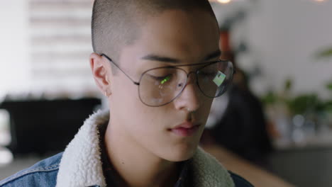 attractive young mixed race man using digital tablet computer in cafe drinking coffee student enjoying watching online entertainment reading social media on portable device wearing glasses