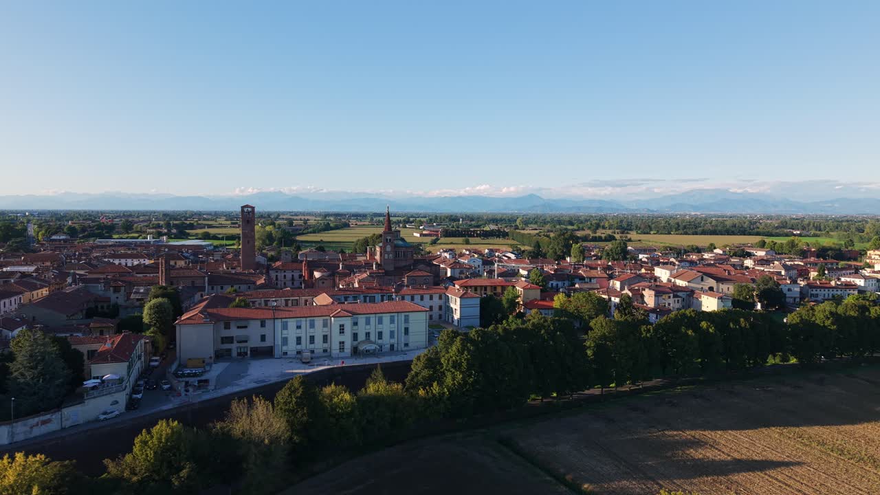Borgo di Soncino con edifici storici e campi verdi circostanti sotto un cielo sereno