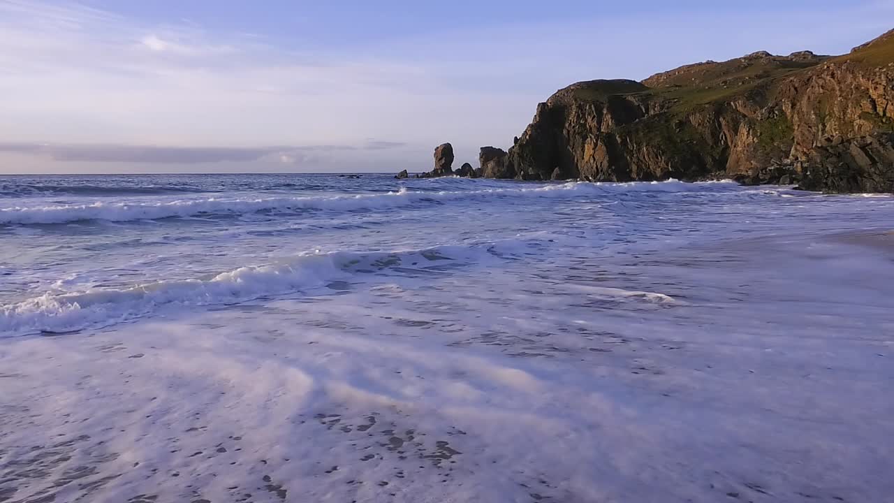 Golden hour shot of some waves, the beach and the headland around Dalmore beach near Carloway