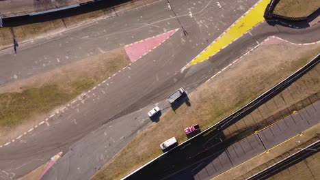 Vista-Aérea-De-Arriba-Hacia-Abajo-Del-Camión-De-Remolque-Despejando-La-Pista-De-Carreras-Retirando-Los-Vehículos-Rotos