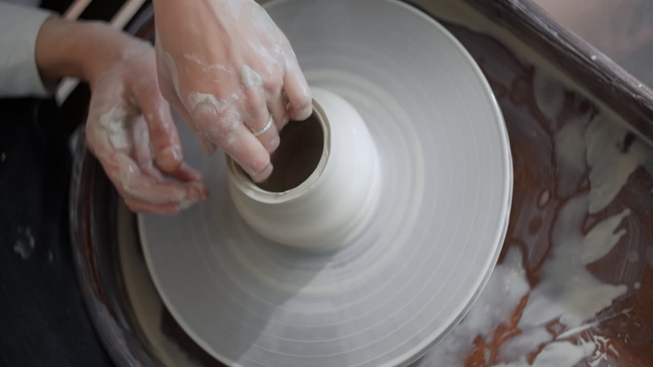 Mãos moldando a argila em uma roda de cerâmica