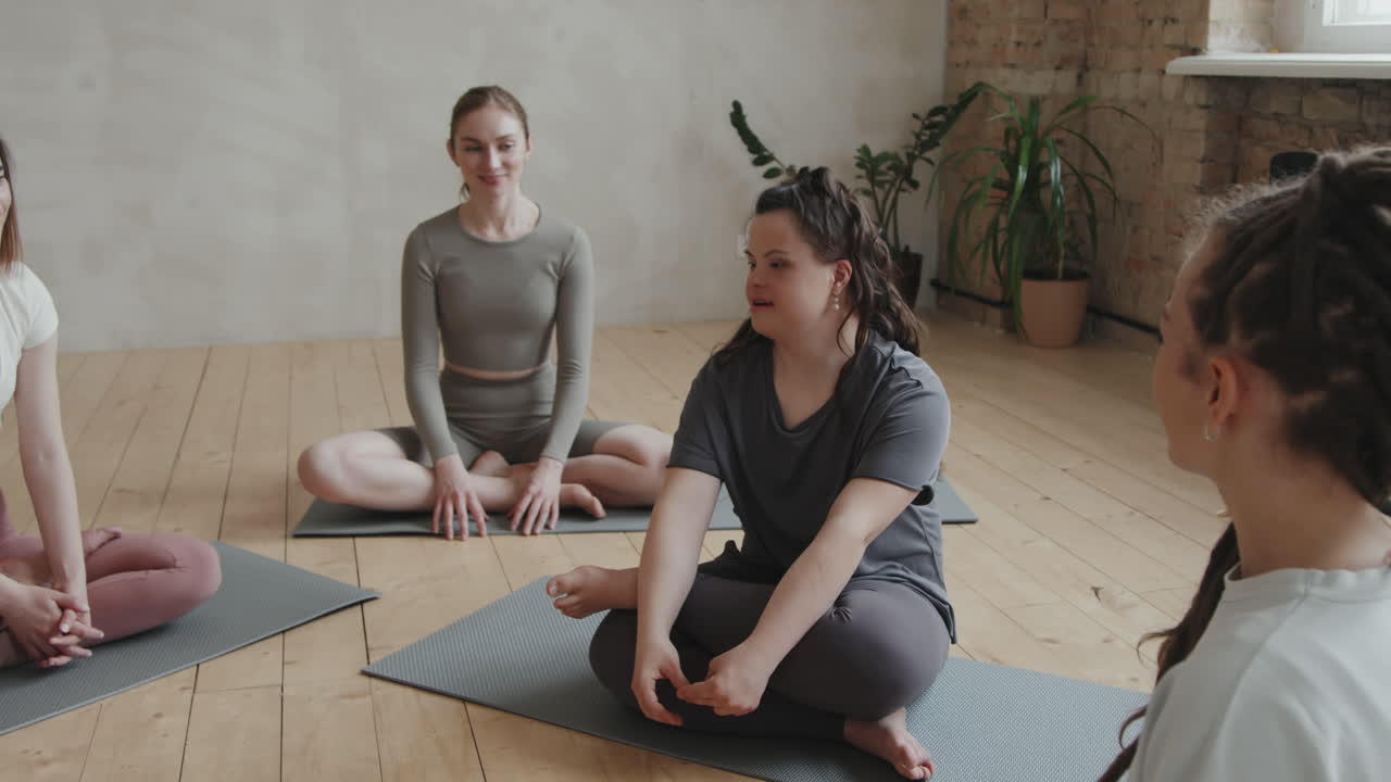 Young Woman With Down Syndrome Talking To Girls At Group Yoga Class