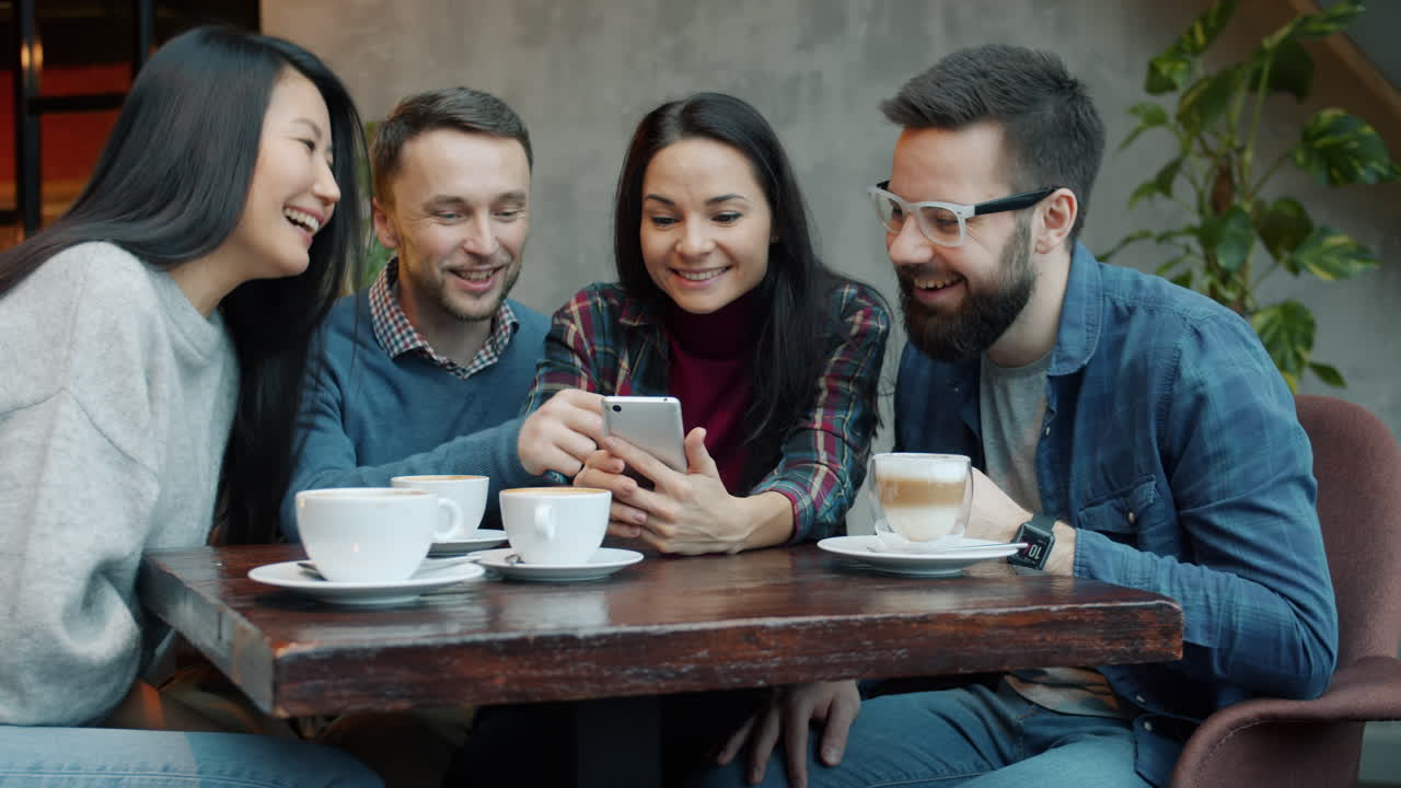 Friends enjoying coffee and looking at a smartphone in a cafe