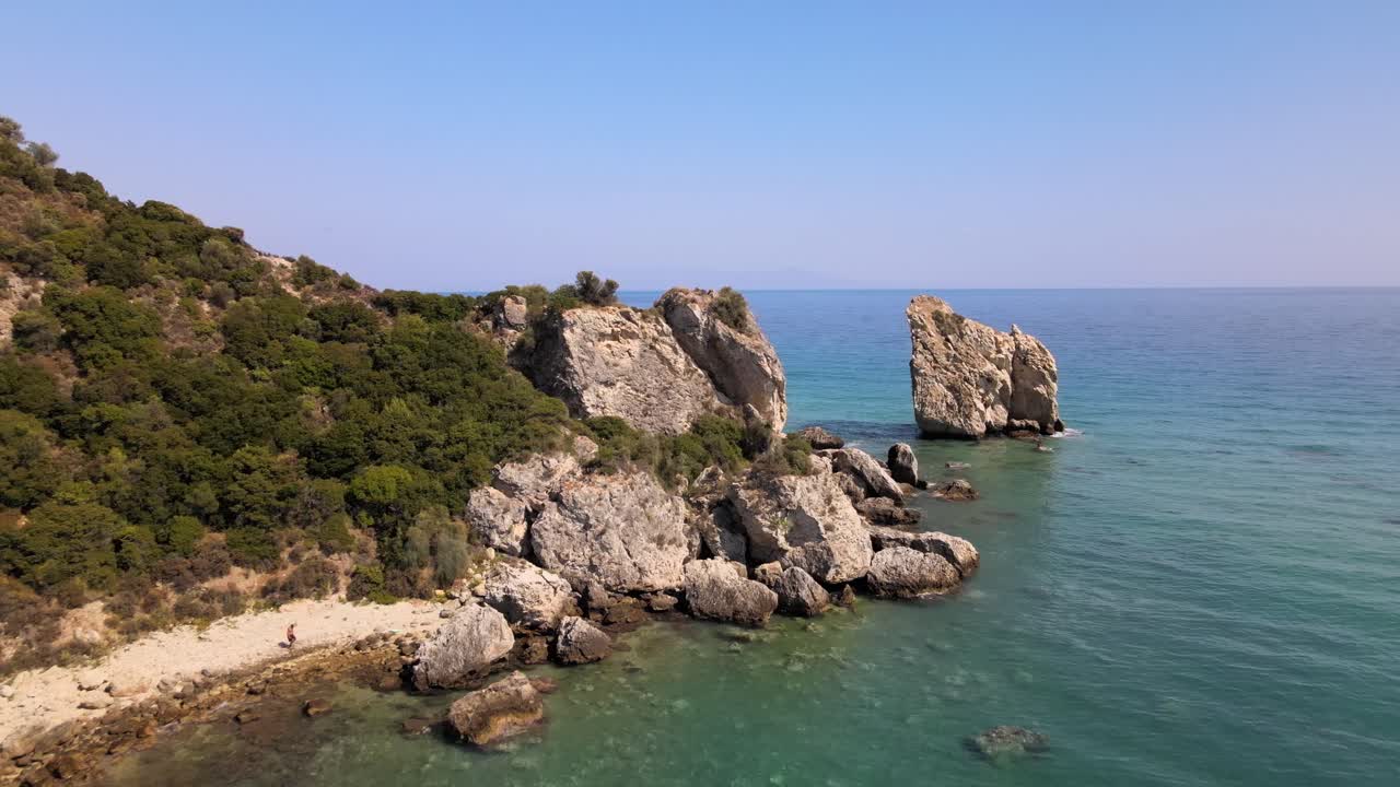 Clip aerea con drone che si sposta su una spiaggia sabbiosa verso una formazione rocciosa a Kavala, Macedonia, Grecia