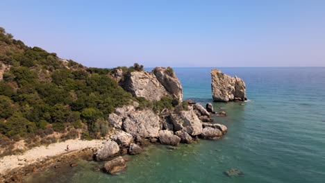 Aerial-drone-clip-moving-over-a-sandy-beach-towards-a-rock-formation-in-Kavala,-Macedonia,-Greece