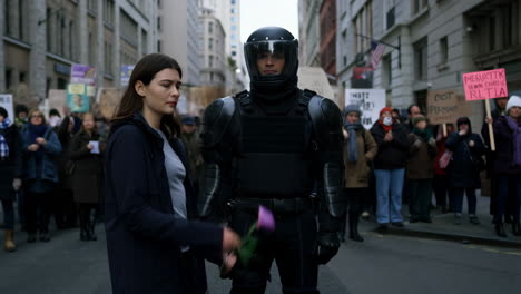 protestor gives flower to riot police officer
