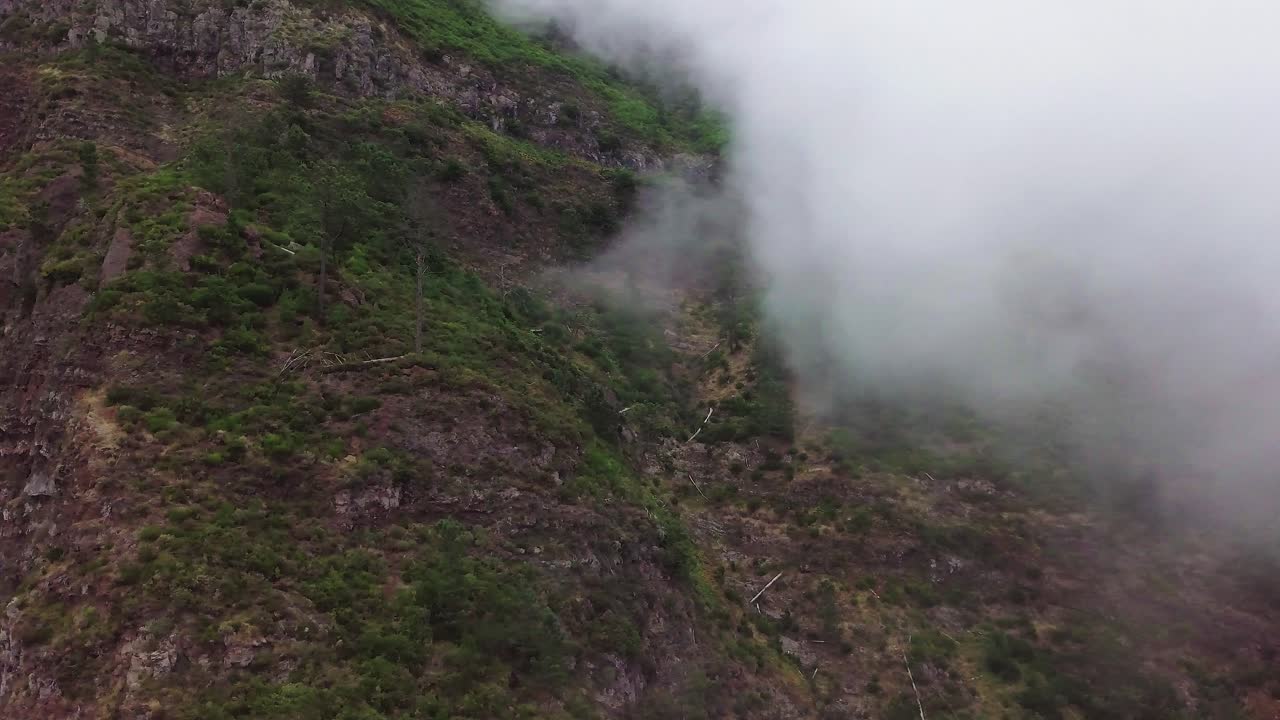 vista escénica del paisaje a través de las nubes desde el mirador de eira do serrado en funchal, portugal - toma de ángulo alto