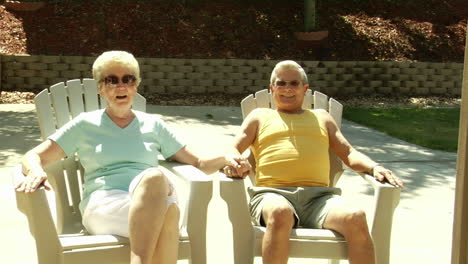 a husband and wife sit in lawn chairs holding hands