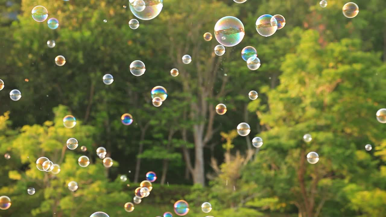 burbujas de jabón flotando en el aire con fondo bokeh verde natural borroso