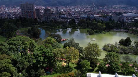 drone shot of novios park and lake, green landscape surrounded by buildings of bogota, colombia