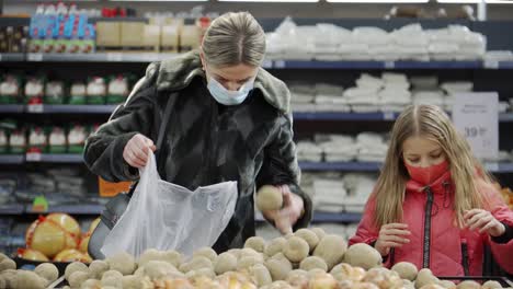 mom and daughter in the grocery store choose vegetables for purchase. a stall with potatoes at the indoor market.