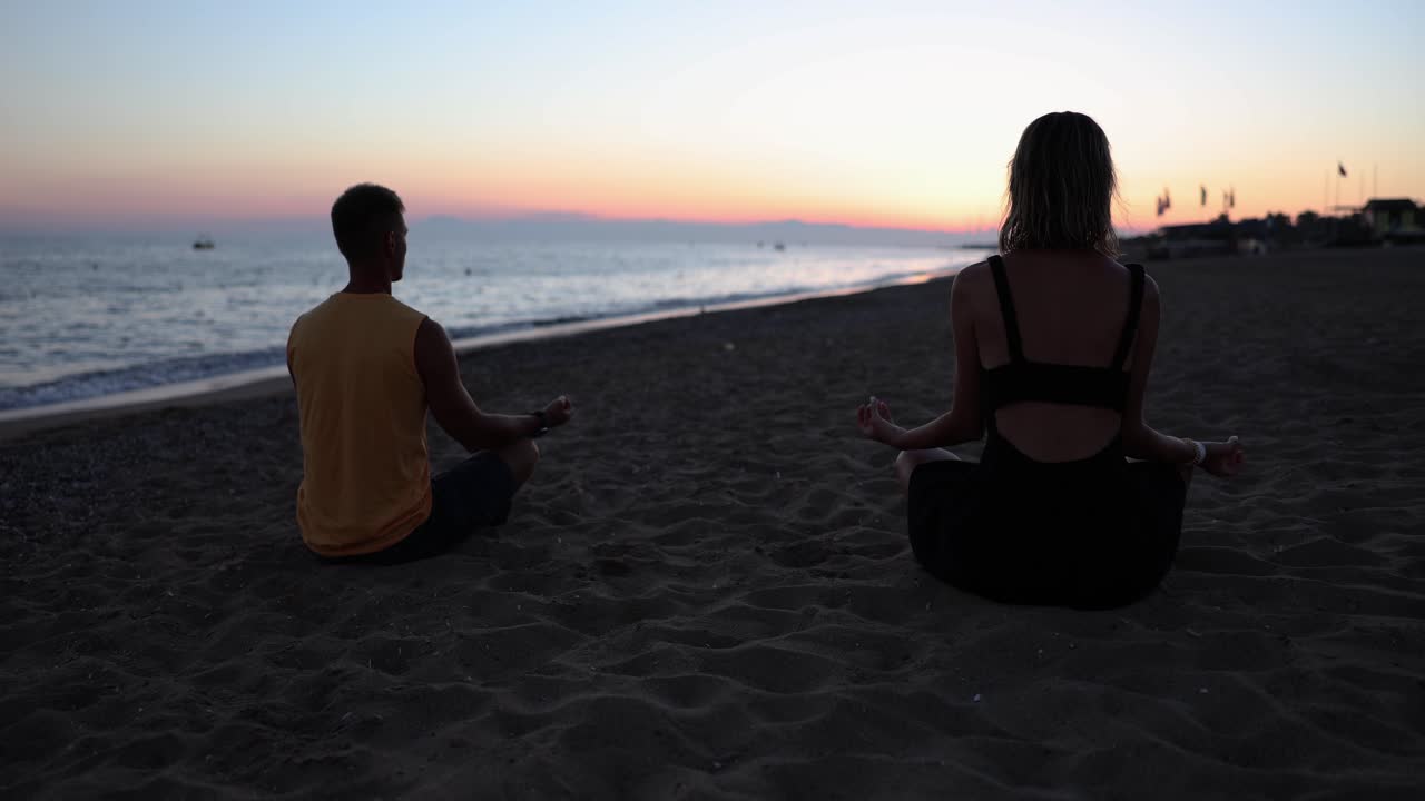 Couple Meditating on the Beach at Sunset