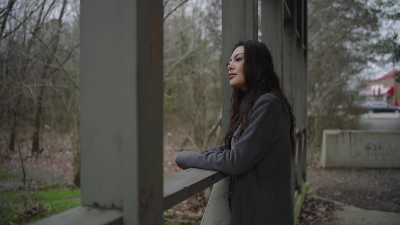 Pretty woman on a wooden bridge turns to camera and smiles with recognition