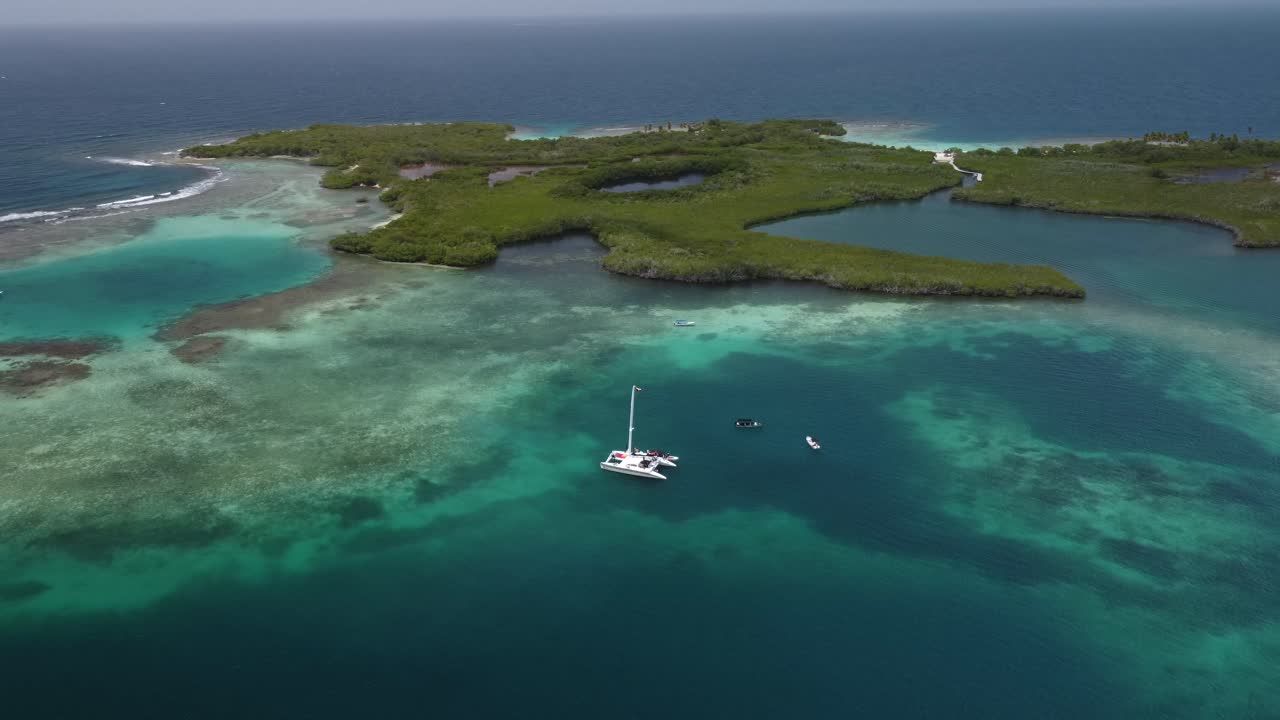 toma aérea de un catamarán o bote en medio de una zona de playa con aguas cristalinas y corales, en tucacas, venezuela
