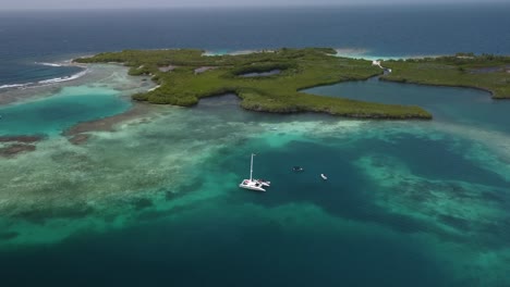 aerial shot of a catamaran or boat in the middle of a beach area with crystal clear waters and corals, in tucacas, venezuela