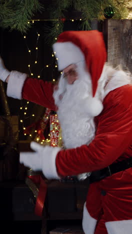 santa claus in red and white costume gesturing a lot. santa with white beard is waving his hands on the background of christmas presents. christmas atmosphere inside the house. vertical video