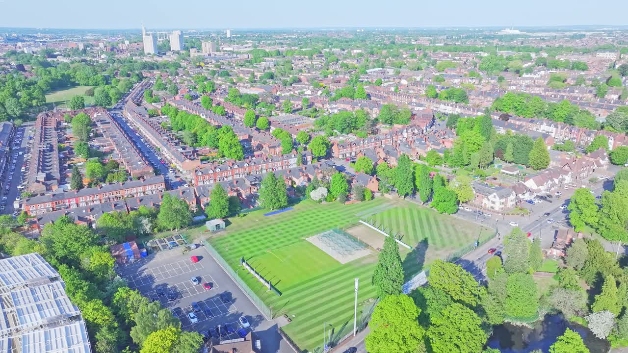 Panoramic aerial view of Cannon Hill Park, Birmingham, UK, showcasing lush green landscape, tree-lined residential streets on a clear sunny day