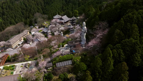 Avalokiteshvara-Stone-Statue-At-Tsubosaka-dera-Temple-With-Sakura-Trees-At-Mount-Tsubosaka-In-Japan