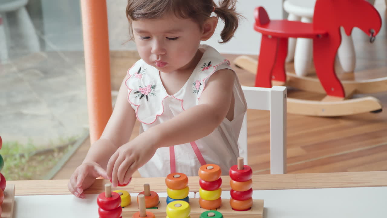 niña preescolar juguetona jugando a contar anillos apilando juguete juego - ángulo alto cámara lenta