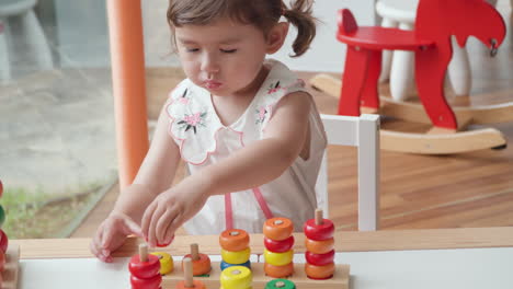 niña preescolar juguetona jugando a contar anillos apilando juguete juego - ángulo alto cámara lenta