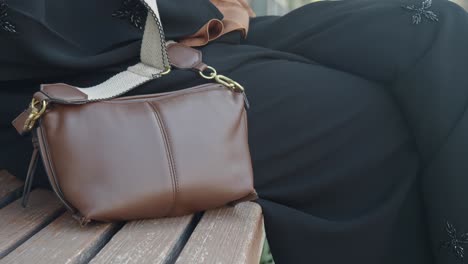 woman sitting on a bench with a brown bag