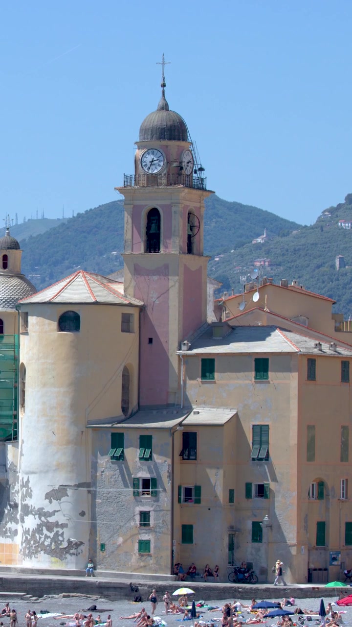 Toma panorámica estática de una iglesia costera y edificios coloridos bajo la brillante luz del sol mediterráneo.