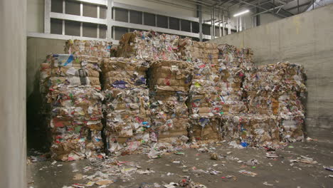 pressed cubes of waste paper, plastic bottles and cardboard at recycling plant, wide shot