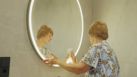 woman cleaning a modern bathroom mirror