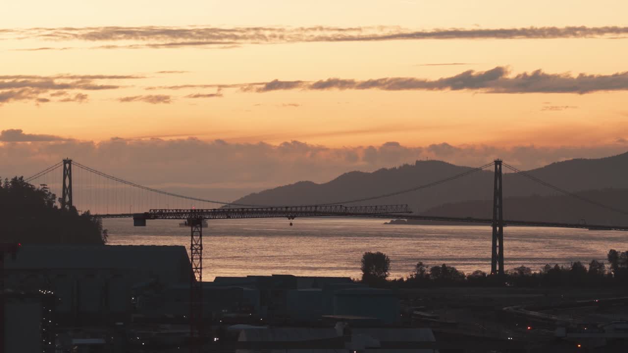 Telephoto aerial rising shot of Lions Gate Bridge at sunset in Vancouver, British Columbia, Canada. 4K