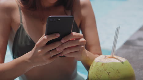 mujer relajándose junto a la piscina con una bebida de coco