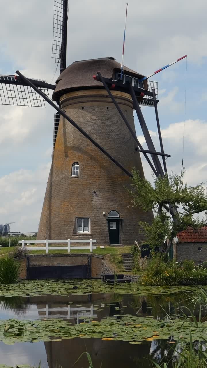 Kincir angin bersejarah di Kinderdijk dengan bayangannya di atas air pada hari musim panas.