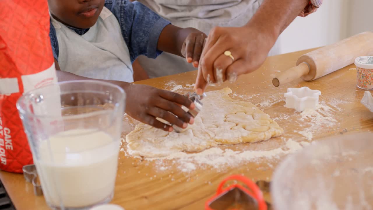 Front view of mid adult black father and son baking cookies in kitchen of comfortable home 4k