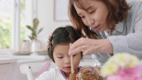 happy asian family eating pancakes for breakfast children enjoying healthy homemade meal with parents on weekend morning in kitchen 4k footage