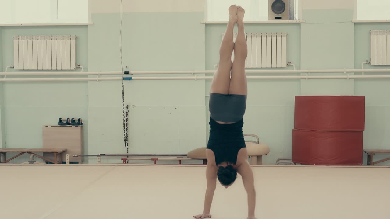 спортивная девушка в тренажерном зале поднимается в руках и идет к камере, вращаясь вокруг своей оси