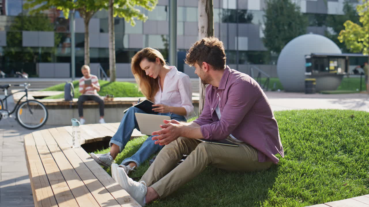 Freelance mand afslutter arbejde i bypark. Smilende kolleger fjernarbejder.