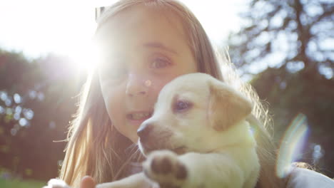 vista cercana de la pequeña y encantadora niña sosteniendo a su cachorro labrador en el parque en un día soleado