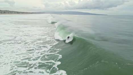 lone surfer skillfully rides massive wave and loses balance as it reaches beach