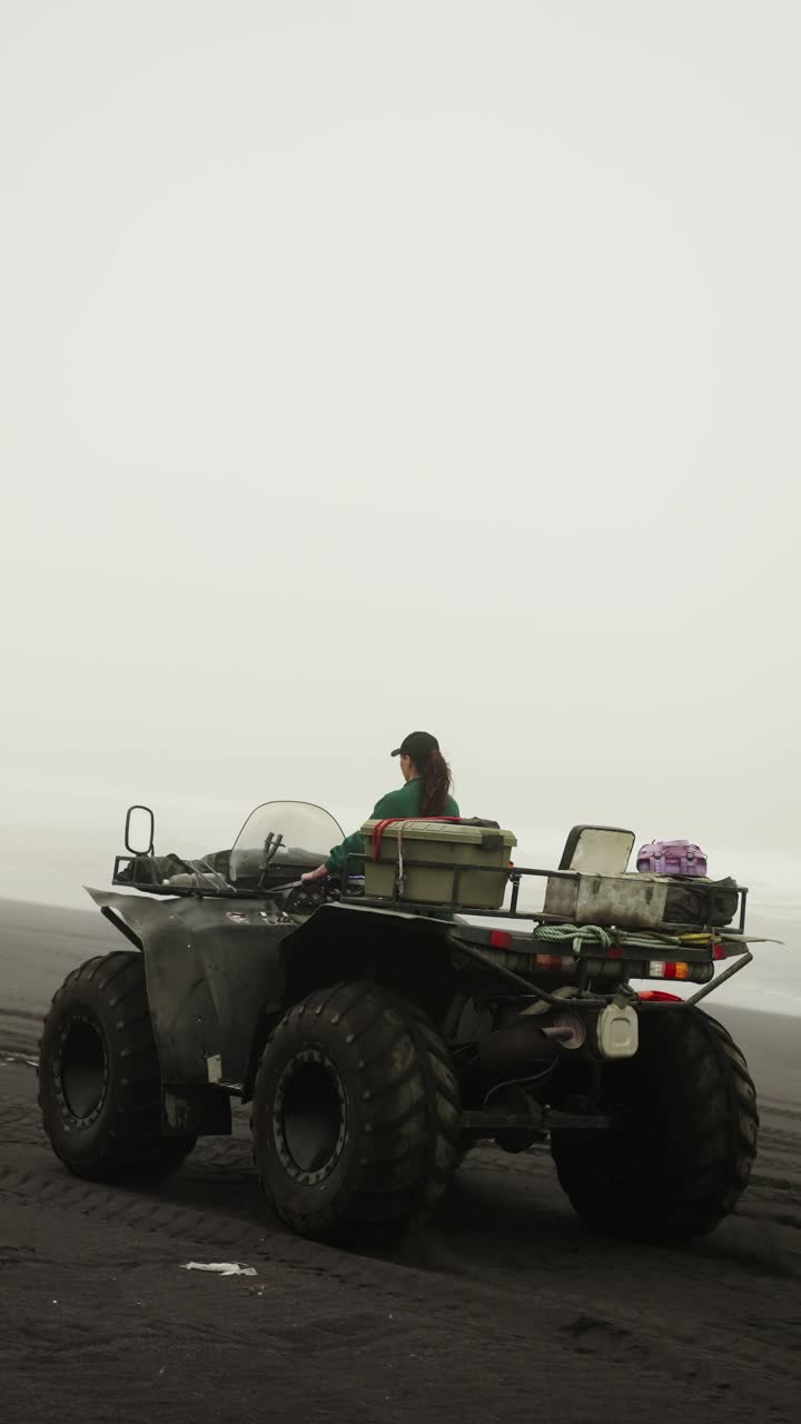 Woman Riding ATV on a Black Sand Beach on a Foggy Day