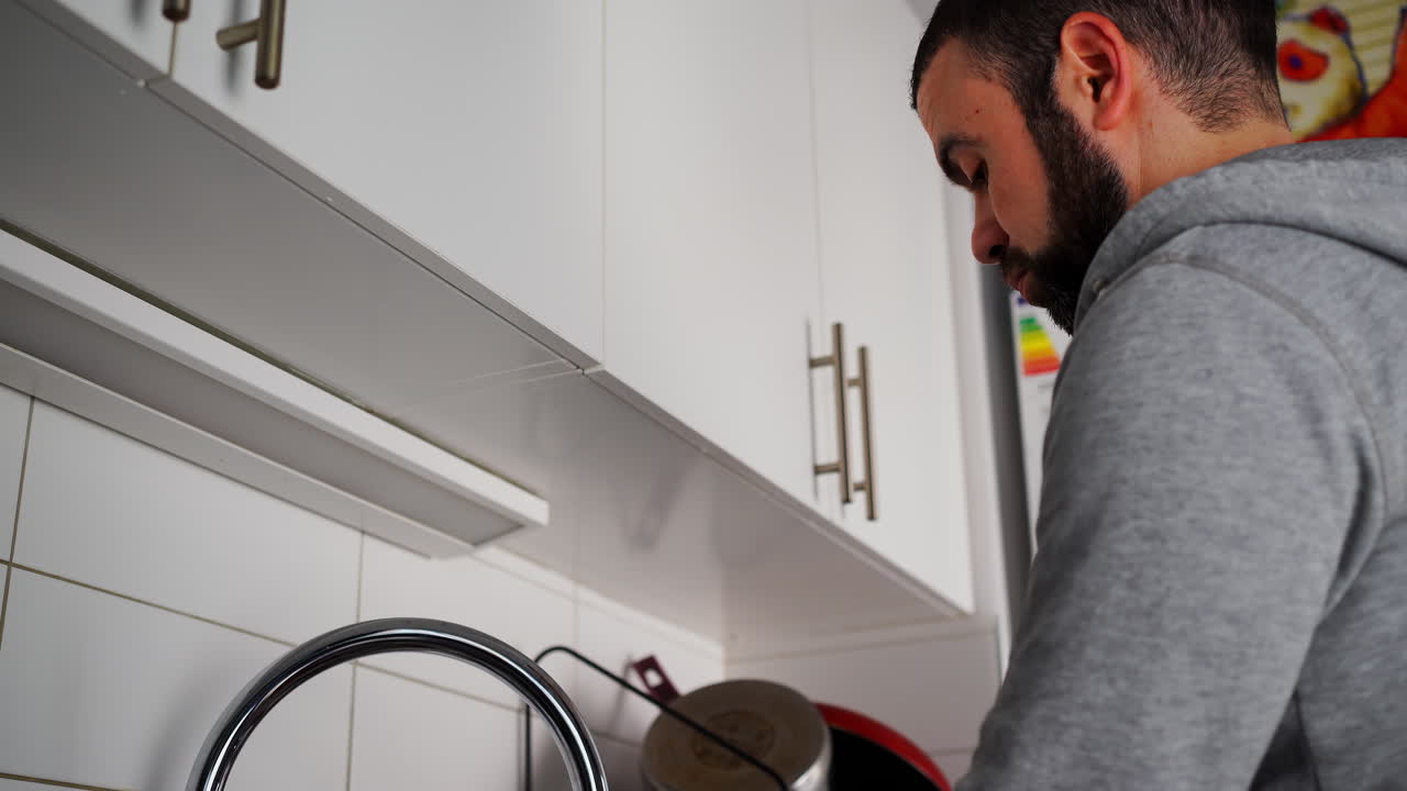 primer plano de un hombre caucásico en la cocina lavando los platos en la casa