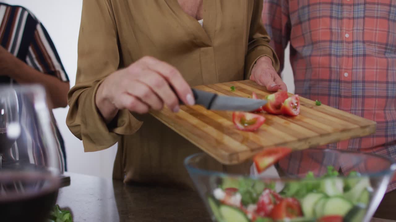 diversas parejas mayores preparando ensalada de verduras en una cocina