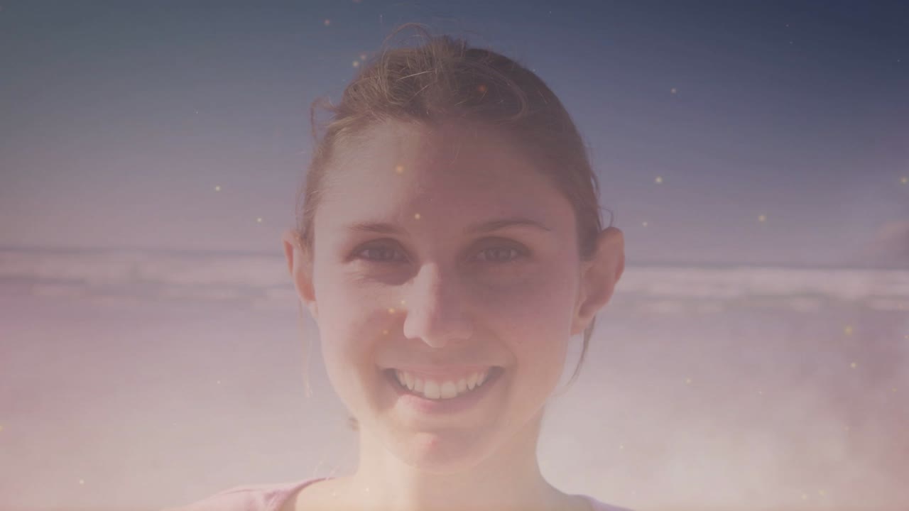 Frau lächelt am Meer in die Kamera, Glitzer-Overlay steigt über dem Gesicht auf und erzeugt eine verträumte Stimmung für Marketing